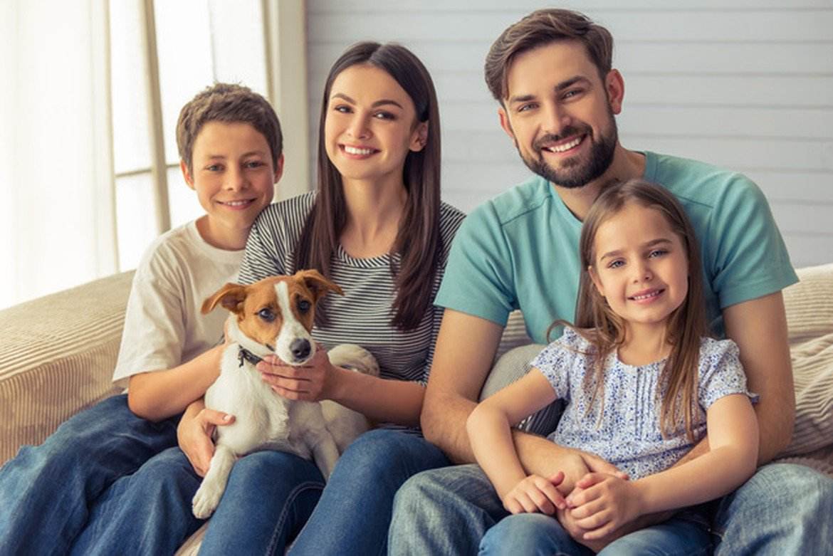 Four people sitting with a dog.